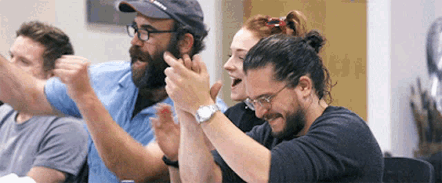 a group of people are sitting at a table with their hands in the air .