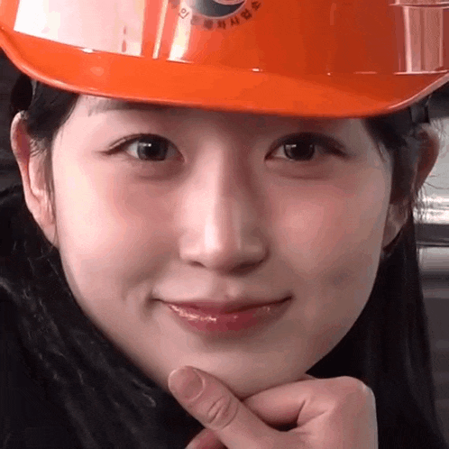 a close up of a woman wearing an orange hard hat that says ' seoul ' on it