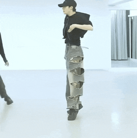 a man wearing ripped jeans and a hat is dancing