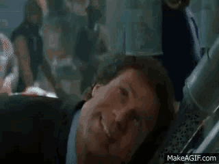a man in a suit and tie is talking to another man in a room .
