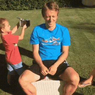 a man wearing a blue shirt with a dolphin on it sits next to a little boy