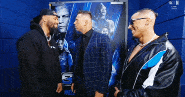two men in suits are standing next to each other in front of a poster .