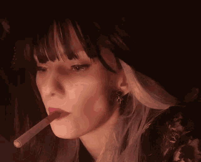a woman is smoking a cigarette in her mouth .