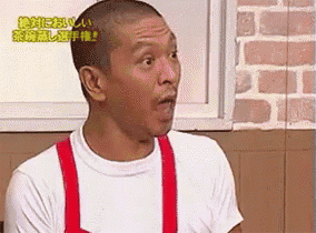 a man with a shaved head is wearing a white shirt and red overalls .