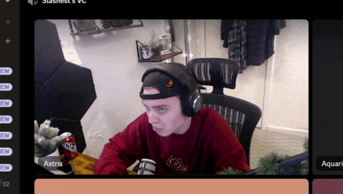 a man wearing headphones sits at a desk in front of a microphone and a can of coke