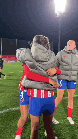 a group of female soccer players hugging each other on the field .
