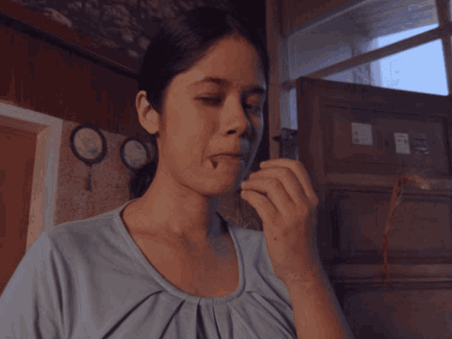 a woman in a blue shirt is eating a chocolate bar