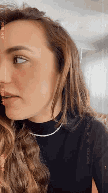 a woman is wearing a black turtleneck and a pearl necklace