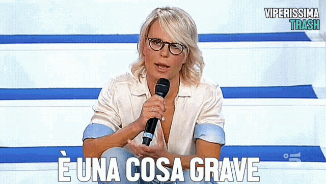 a woman holding a microphone with the words e una cosa grave written below her