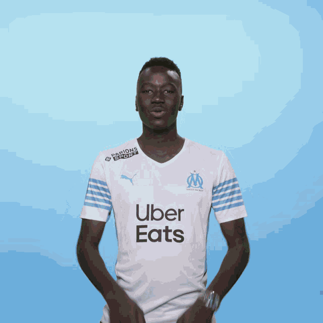 a man wearing an uber eats shirt is pointing
