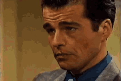 a man in a suit and tie is looking at the camera with a serious look on his face .