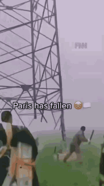 a group of people standing in front of a tower that says paris has fallen on it