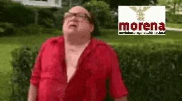 a man in a red shirt is standing in front of a morena sign