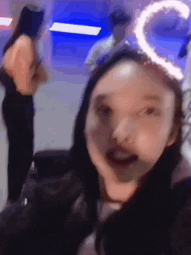 a woman is making a funny face in a blurry photo while a man stands behind her .