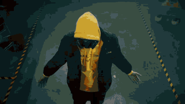 a man wearing a gas mask and a yellow hoodie with the letter a on it