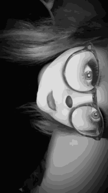 a black and white photo of a woman wearing glasses and makeup