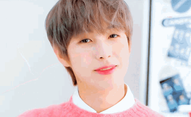 a close up of a person 's face with a pink sweater on