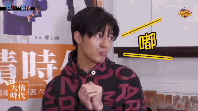 a man wearing a red and black sweatshirt with chinese writing on it