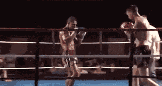 two men are fighting in a boxing ring and one of them is wearing boxing gloves
