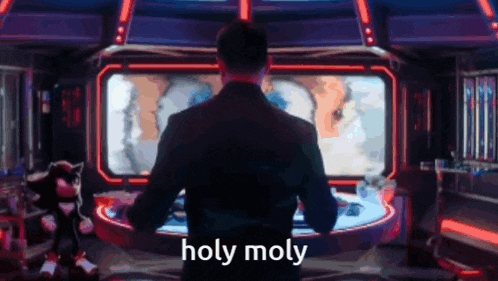 a man in a suit is standing in front of a computer screen that says holy moly