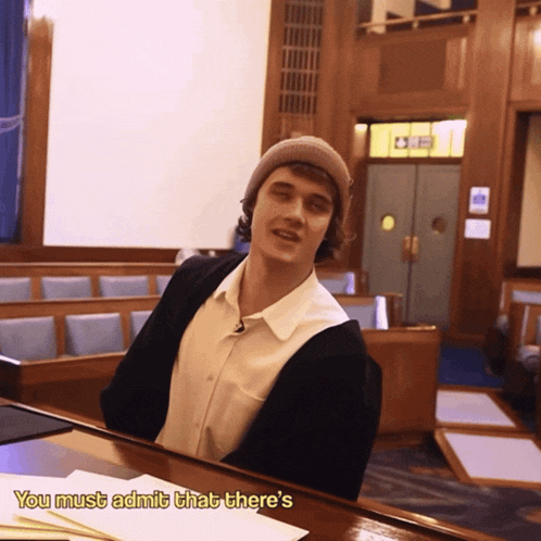 a man sitting at a table with the words " you must admit that there 's " on the bottom
