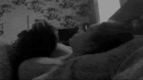 a black and white photo of a woman laying on top of a man .