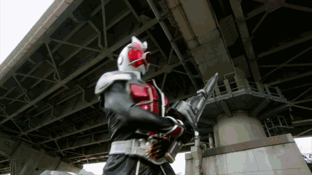 a man in a superhero costume is standing under a bridge holding a sword