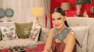 a woman is sitting on a couch in a living room smiling at the camera .