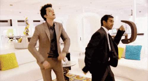 two men in suits and ties are dancing in a living room .