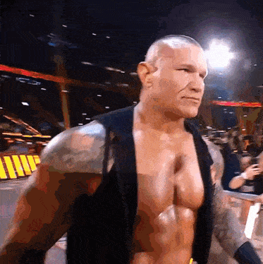 a man without a shirt is standing in front of a sign that says ' wwe ' on it