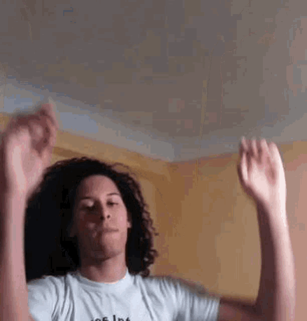 a man with curly hair is dancing with his hands in the air .
