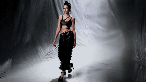 a woman in a black crop top and pants is walking on a runway