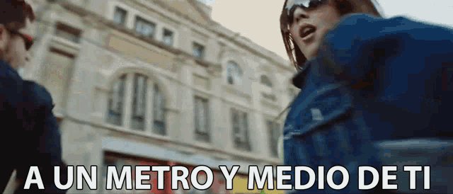 a man and a woman standing in front of a building with the words a un metro y medio de ti