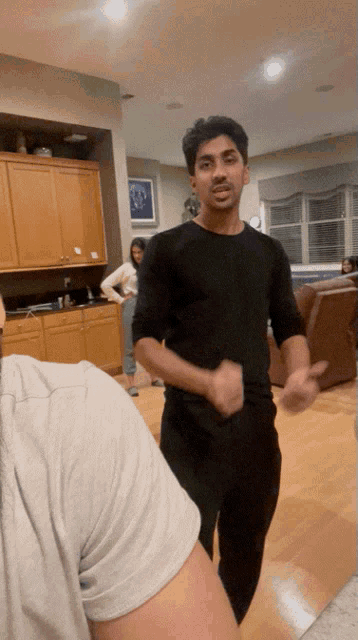 a man in a black shirt is dancing in a room