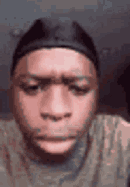 a close up of a man 's face wearing a hat and a t-shirt .