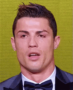 a close up of a man in a suit and bow tie with a tear running down his face