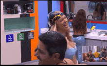 a man and a woman are laughing in a kitchen with a sign that says ' smoking ' on it