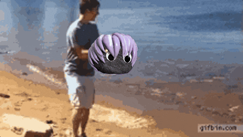 a man holding a purple helmet on the beach