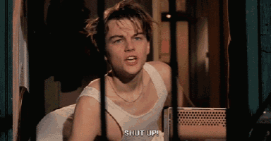 a man in a white tank top is saying " shut up "