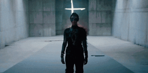 a woman is standing in front of a cross in a dark room