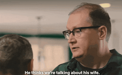a man with glasses is talking to another man and says he thinks we are talking about his wife