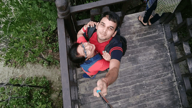 a man and a woman are posing for a picture on a wooden staircase