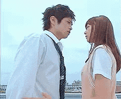 a man and a woman are standing next to each other looking at each other .
