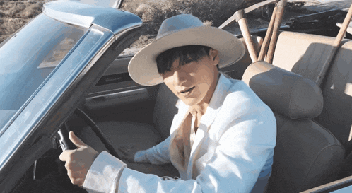a man in a cowboy hat is giving a thumbs up while sitting in a car