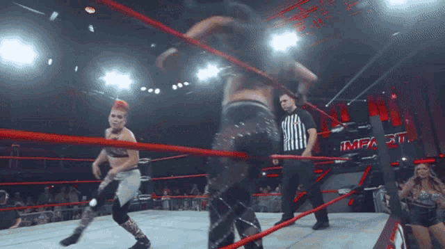 two women are wrestling in a ring with a referee and the word impact on the wall behind them