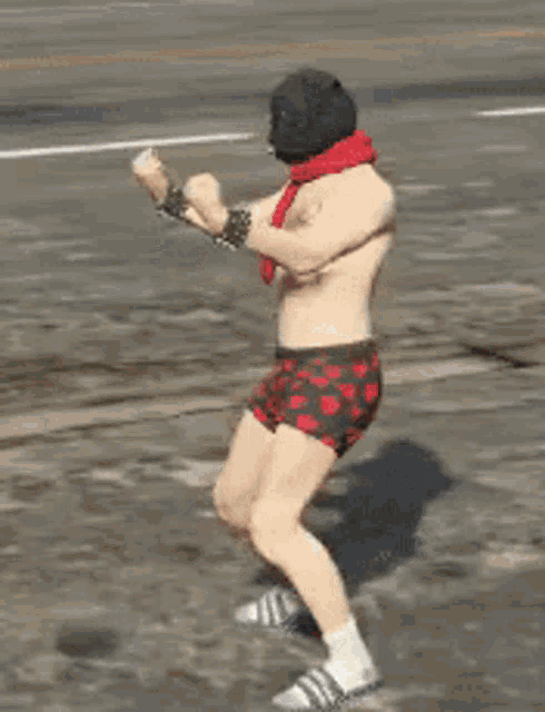 a shirtless man wearing boxer shorts and a scarf is dancing on a street .
