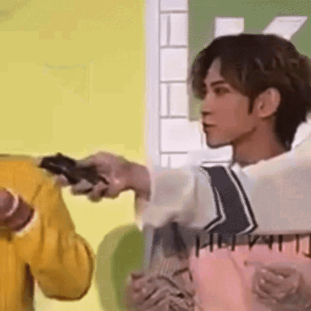 a man is pointing a gun at another man while holding a video game controller .