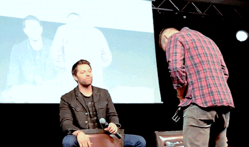 a man in a plaid shirt is kneeling down next to another man