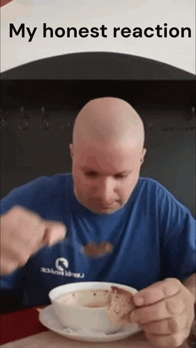 a bald man in a blue shirt is eating a bowl of soup with a spoon .
