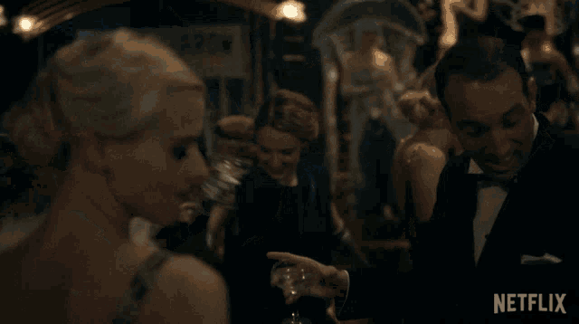 a man in a tuxedo talks to a woman in a black dress in front of a sign that says comet awards